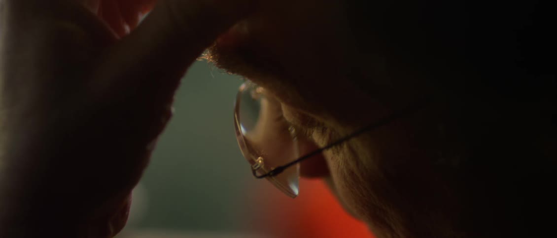 A man wearing glasses holds his head