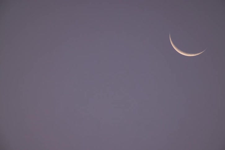 Crescent moon visible in the sky with a softtoned background