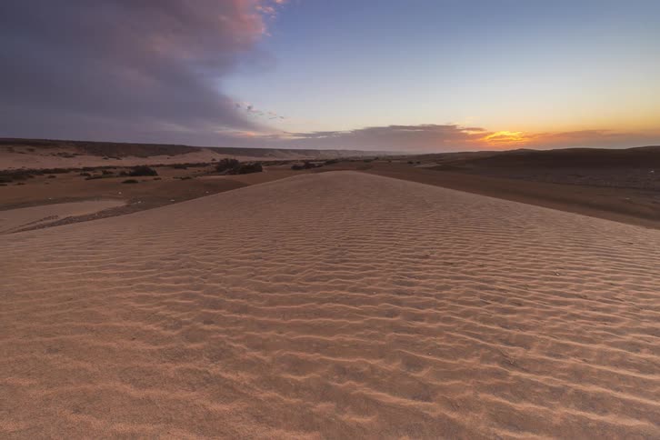 Sand dune with rippled patterns under an evening sky