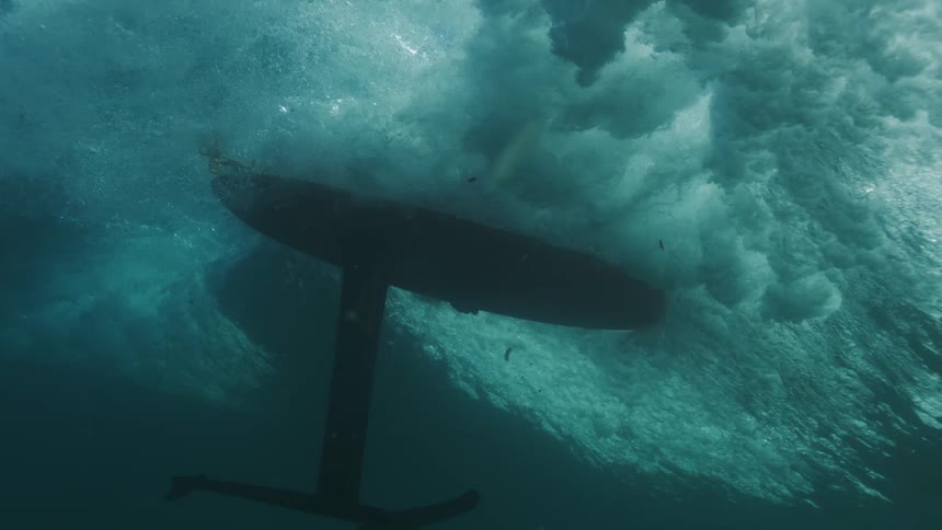 Hydrofoil board moving beneath a wave in the ocean