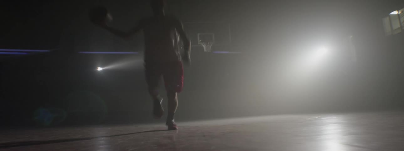 A man is running on a court and dribbling a basketball