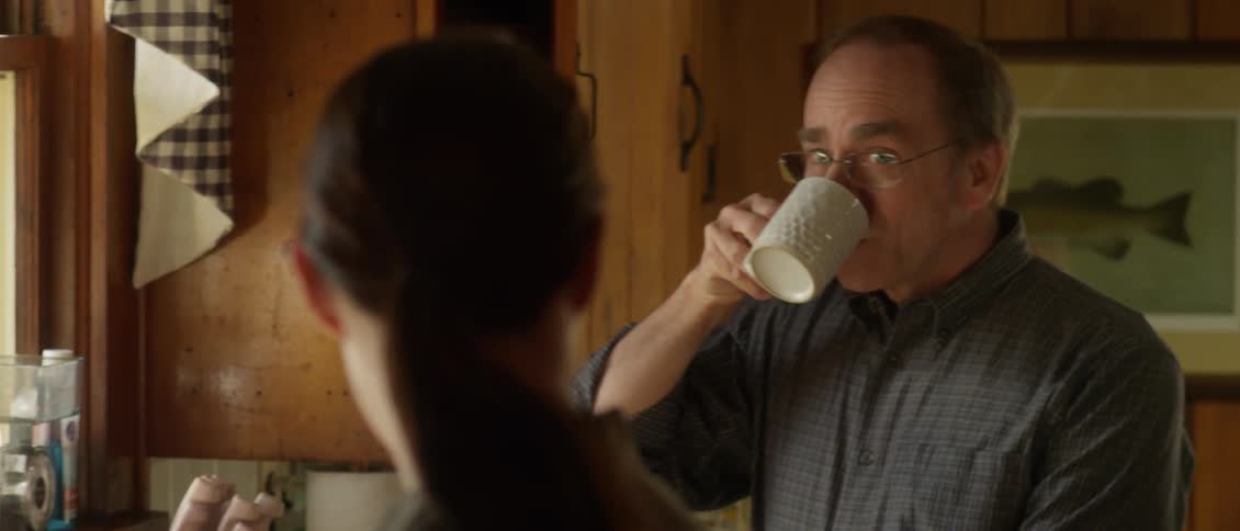 A woman speaks to a man drinking from a cup