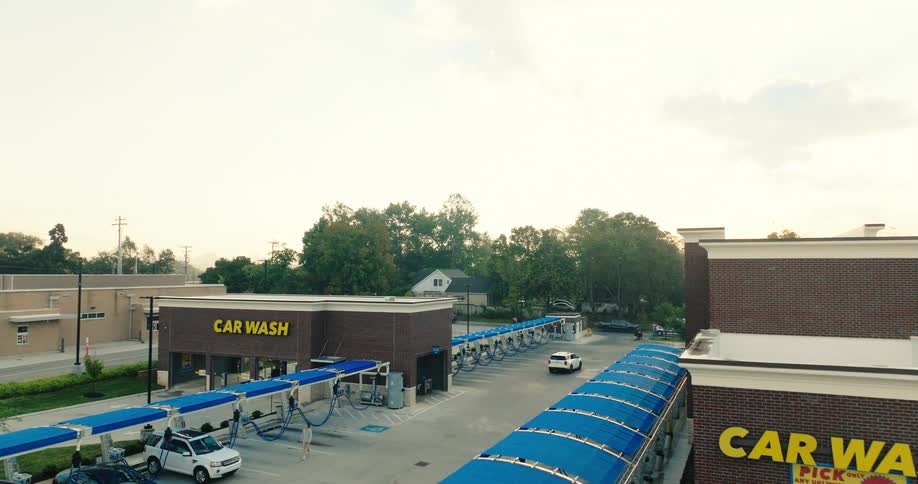Car wash facility with multiple covered bays and parked vehicles