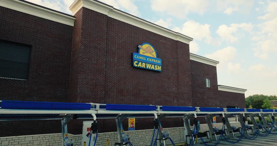 A car wash building with the camel express car wash logo on the wall at midday
