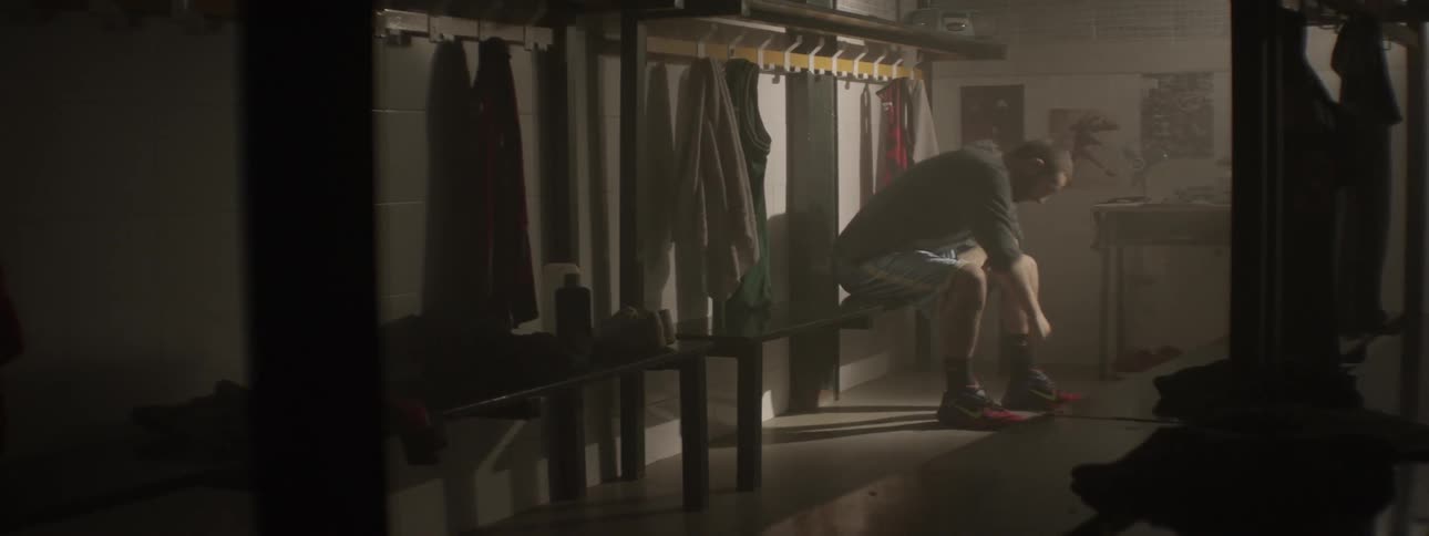 Man sitting on a locker room bench and looking frustrated