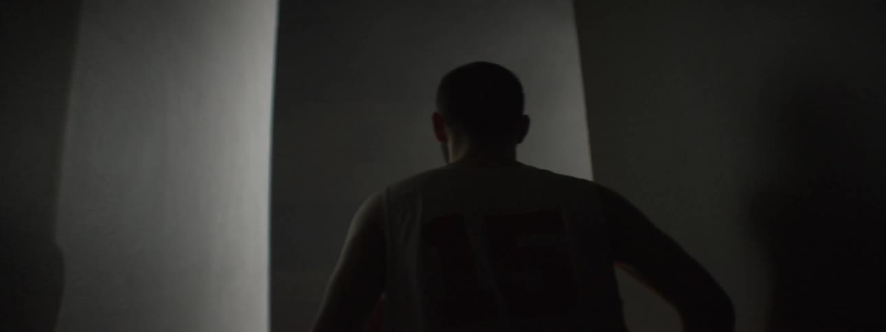 Man with basketball jogging into a dimly lit sports auditorium