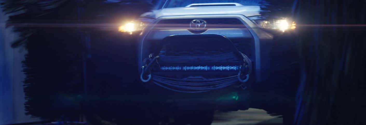 An off road vehicle passes through an automated car wash at night