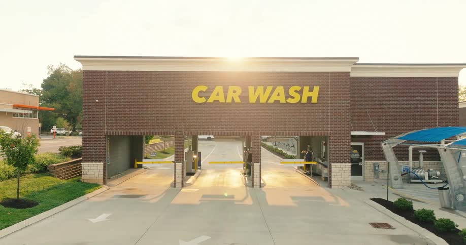 Car wash building with three wash entrances and car wash sign on the facade