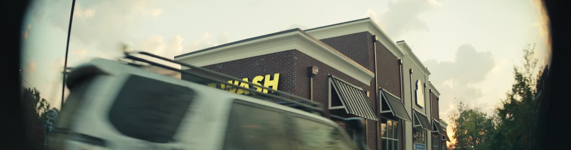 A vehicle drives toward the door of a car wash