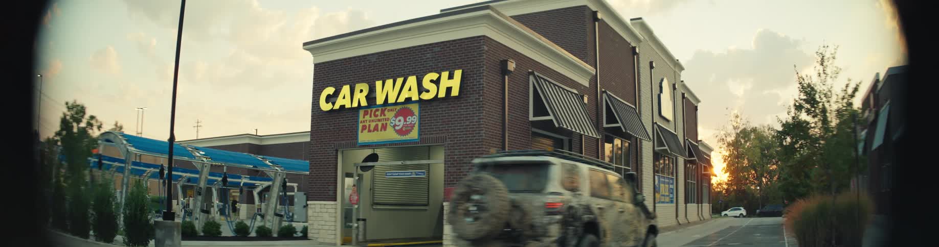 Car wash building with a car wash sign beside a covered vehicle cleaning area