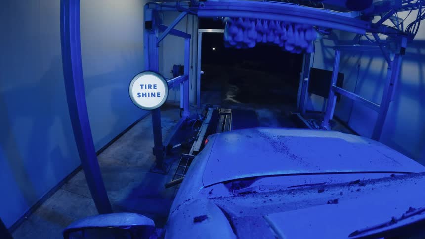 Car moving through an automatic wash system with brushes and rails