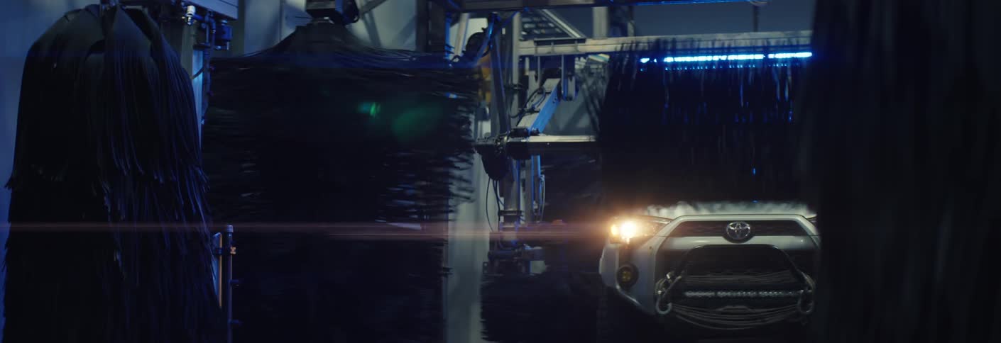 Automobile moving through a car wash as the machines spin to clean the vehicle exterior