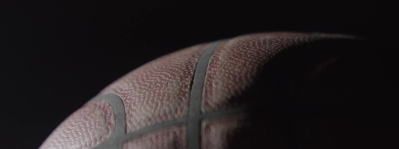 Extreme close up of a portion of a basketball with a hand starting to cover it