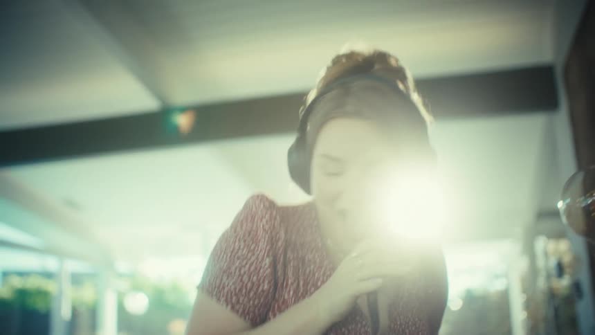 Woman wearing headphones sings using her smartphone as a microphone