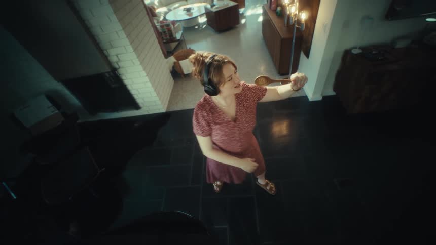 Woman singing with headphones and wooden spoon