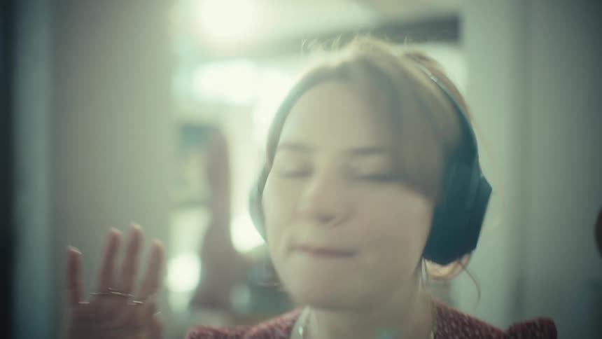 The woman is dancing and singing into a spoon at home