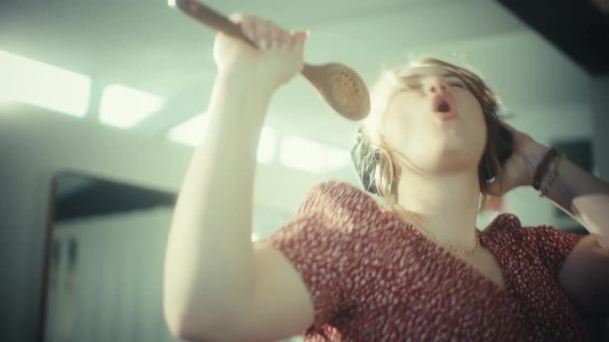 Woman singing with headphones and wooden spoon