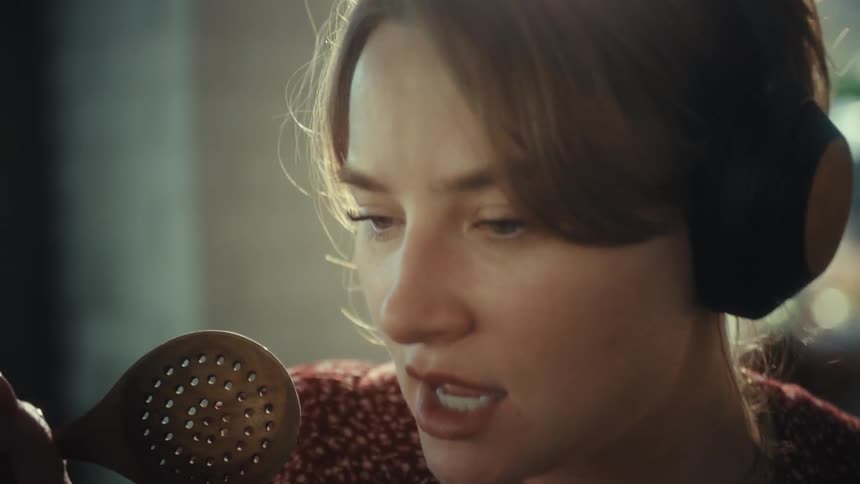 Woman singing with headphones and wooden spoon