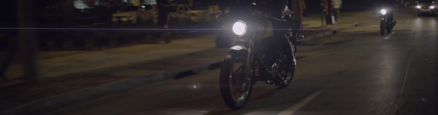 Motorcyclist rides down a city road at night