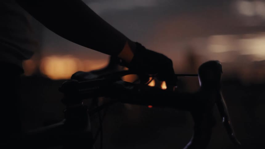 Hand holds a bicycle handlebar against the sunset sky