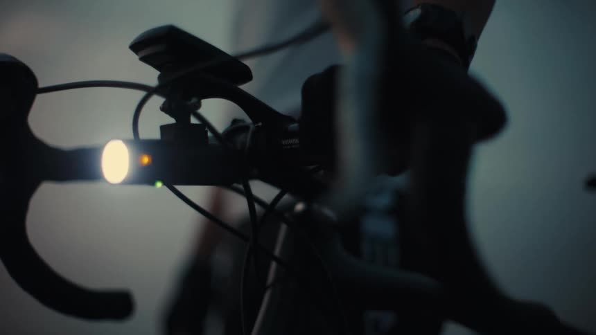 Cyclist turns the handlebars of a bicycle while the headlight glares
