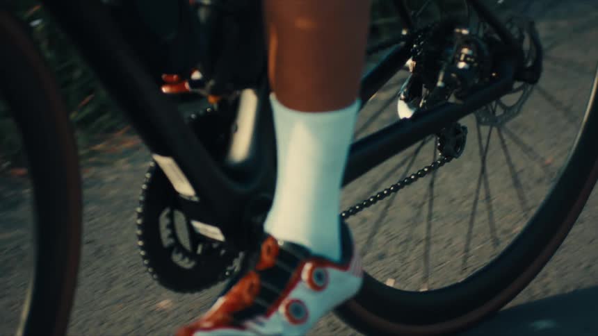Cyclist pedals their bicycle along an asphalt path on a summer day