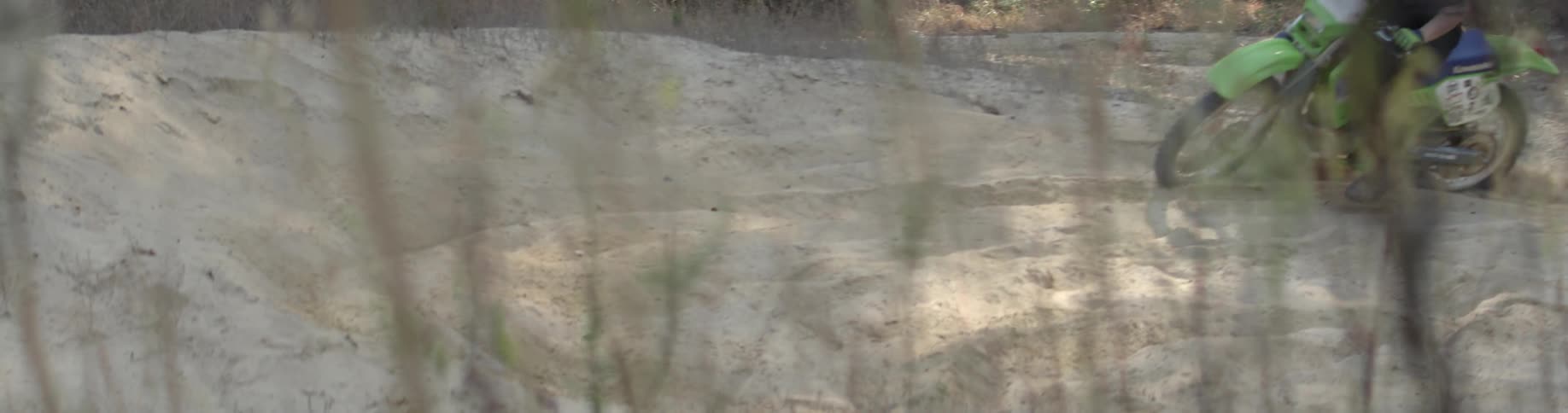 A dirt bike rides through a sandy area