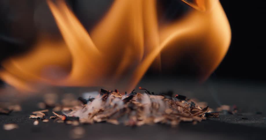 A close up of some wood chips being lit on fire with a torch