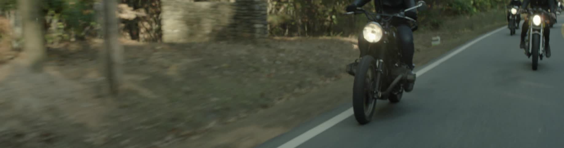 Two people ride motorcycles in a rural setting