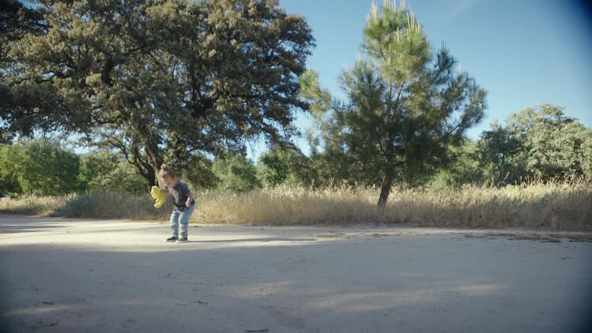 Little girl holding a toy jumping through the vegetation