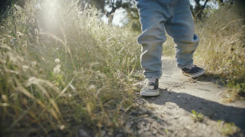 Child in jeans walking along a trail during the day