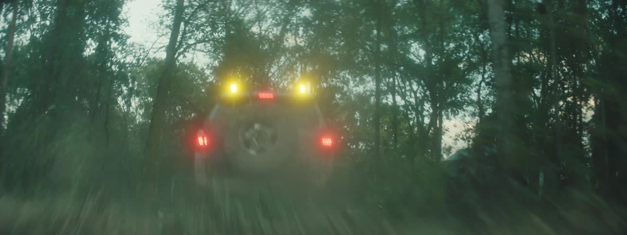 Jeep traveling on a rough rural road past a house and into the woods