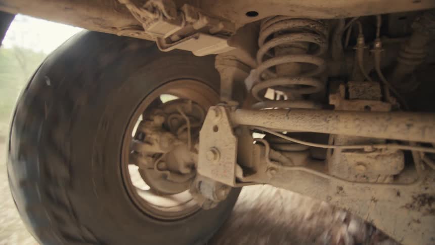Dusty vehicle wheel traversing a dirt track