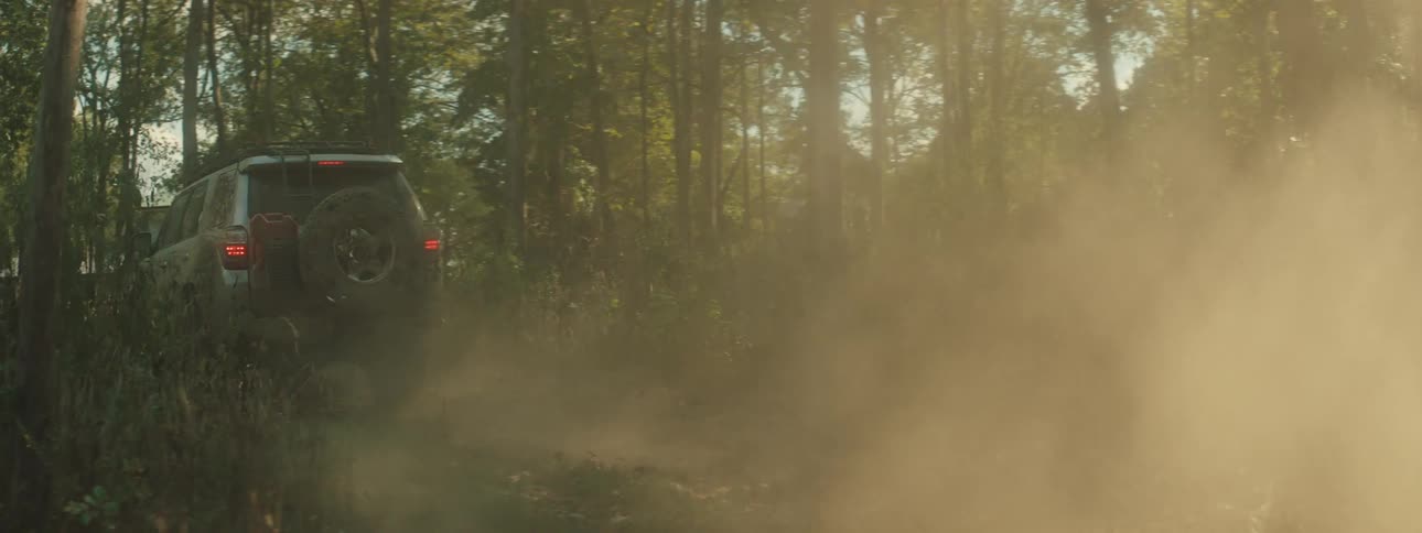 Pickup truck making a turn and kicking up dust on a forest trail