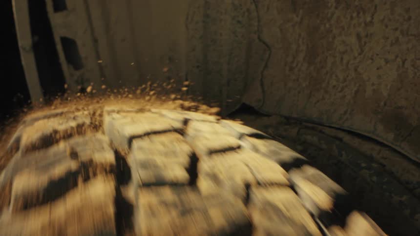 An extreme close view shows a dirty tire beginning to spin and throwing off bits of dried mud and dust