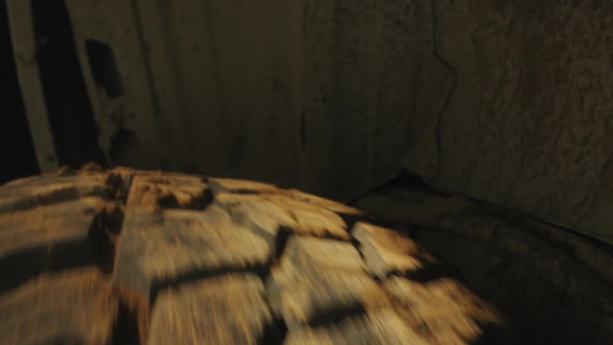 A close up shot focuses on the heavy tread of a dirty tire as it spins rapidly inside a dark wheel well kicking up small pieces of dried mud and dust while the vehicle travels over rough terrain