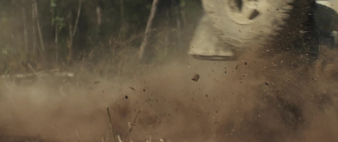 An off road suv kicking up dust on a rugged forest trail in sharp focus with a softly blurred background