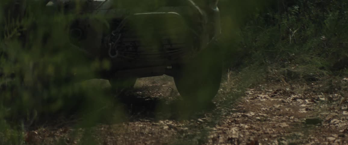 An offroad suv driving through a forest at midday