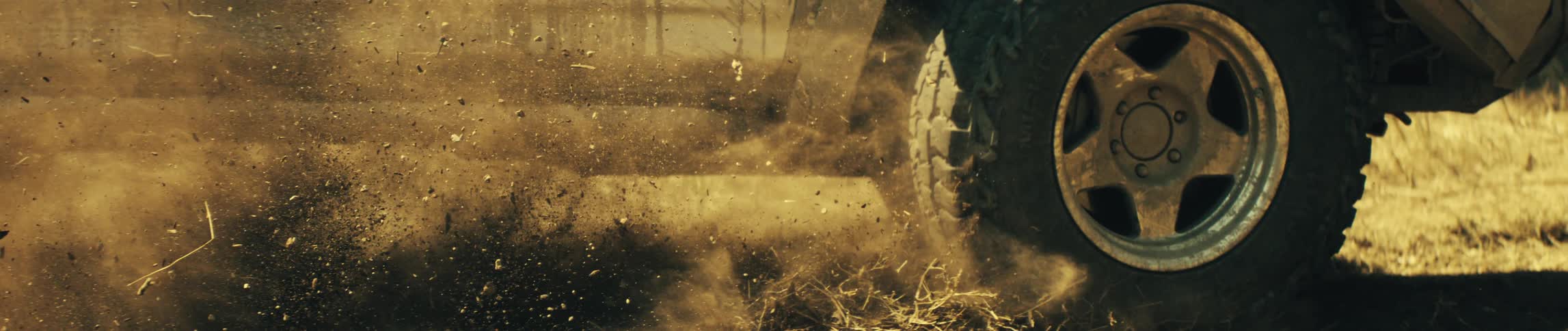 Suv wheel throws dirt and debris while accelerating on a dirt road
