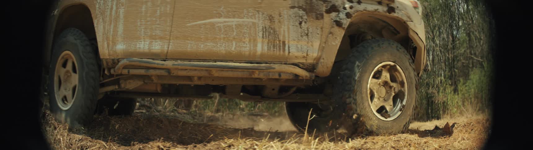 Wheels turn on a truck as it moves on a dirt road in the woods
