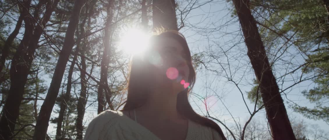A woman is in the woods on a windy day