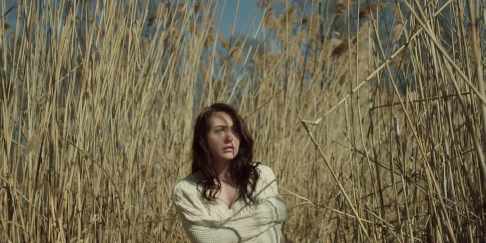 Woman stands beside tall brown plants