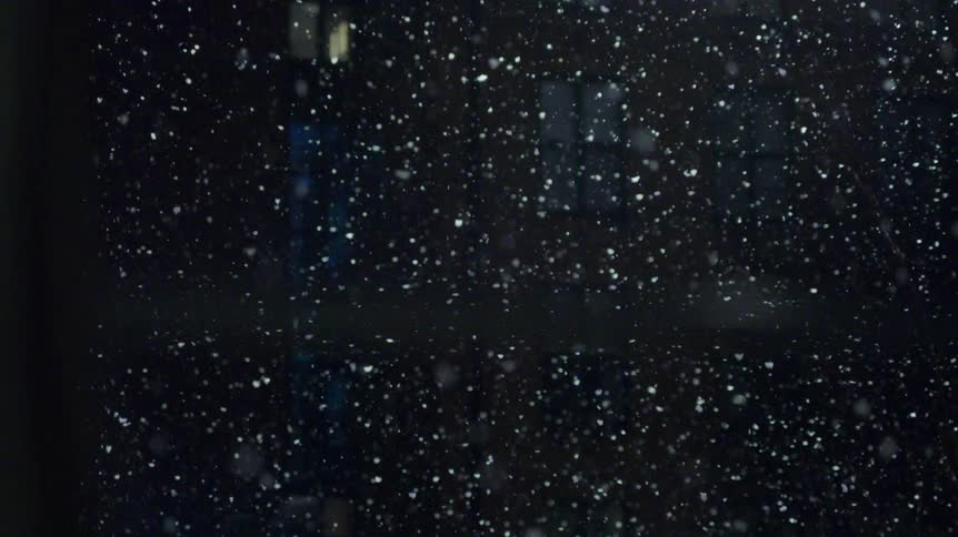 The snow is falling at night in front of the building