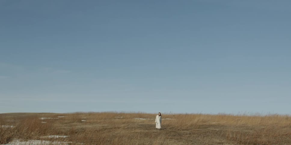 A woman in white walks on the field ahead