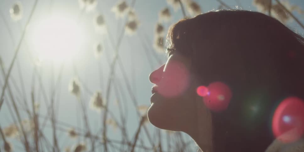 Woman sitting in the sun beside plants
