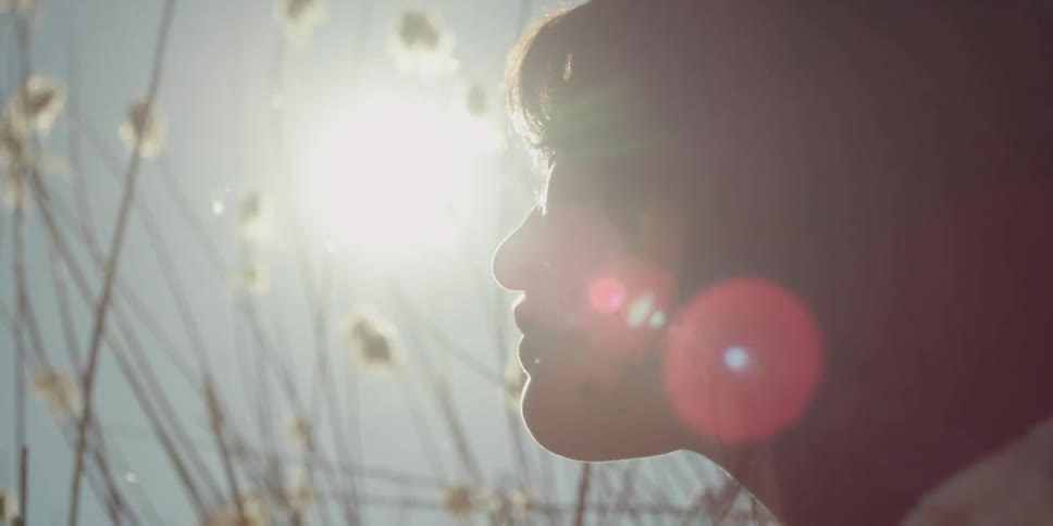 Woman sits among weeds on a sunny day