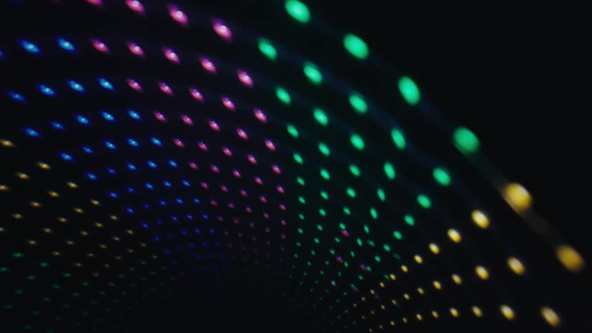 Glowing orbs of colored lights move across the darkness in a curved arched formation