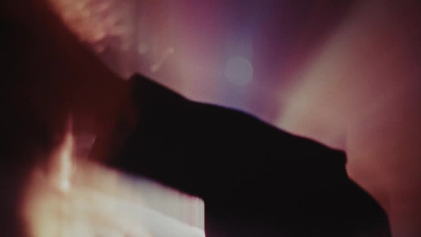 A woman with long hair is shown in a dark environment with light leaks and lens flares