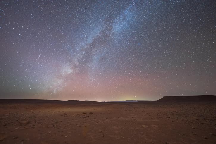 Starry sky with the milky way band above a desert plain at night