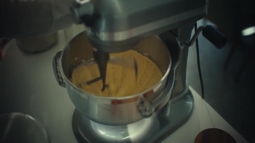 Stand mixer mixes batter in a metal bowl on a kitchen counter
